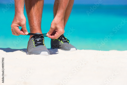 Young male runner getting ready to start on white beach photo