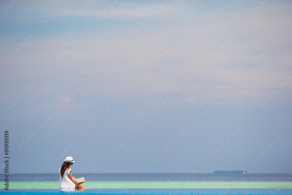 Young girl reading book near swimming pool Young girl reading book near swimming pool