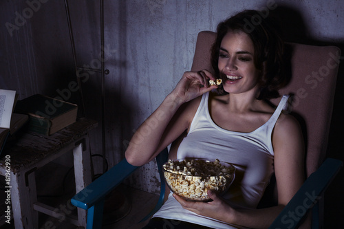 woman with popcorn watching movie and laughing 