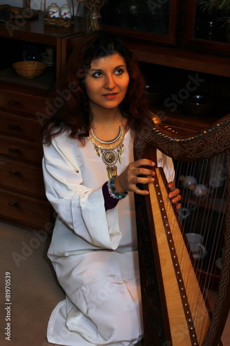 Young woman playing celtic harp in a historical costume
