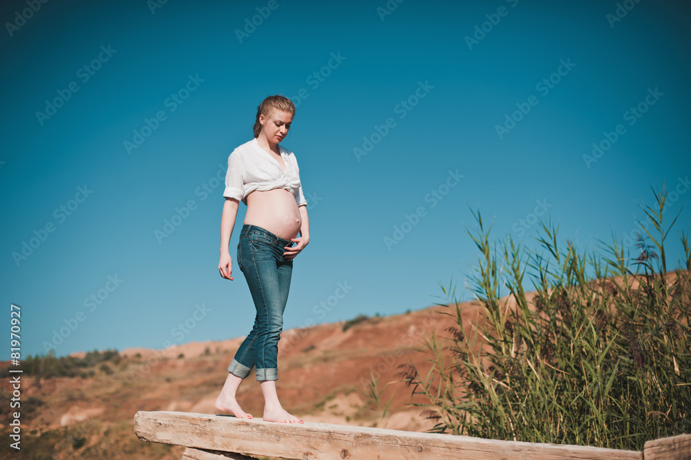 Beautiful young pregnant woman going on the pier on a blue lake, Beautiful young pregnant woman going on the pier on a blue lake,