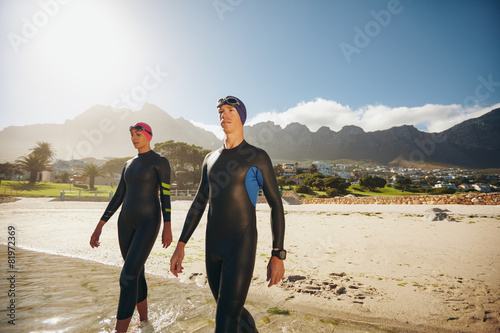 Canvastavla Young triathletes walking into the sea wearing wetsuit