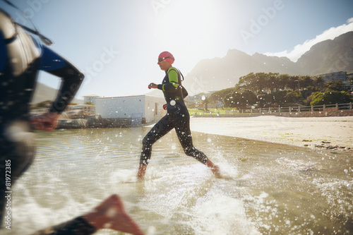 Fotografie Participants running into the water for start of a triathlon
