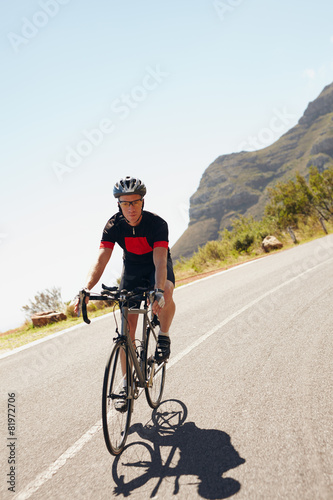 Male cyclist riding down a country road