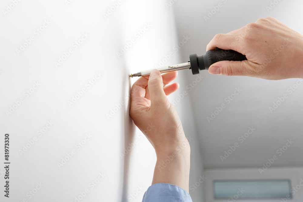 Worker manually tightening hang screw