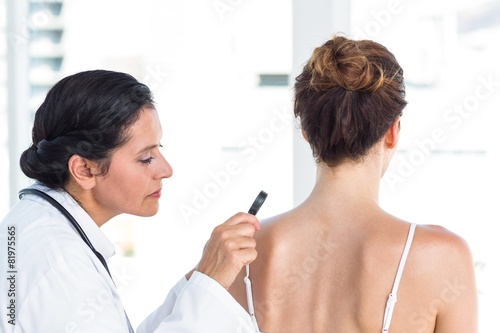 Doctor examining patient with magnifying glass