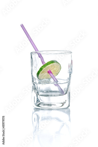 Vodka with lime and drinking straw in a glass