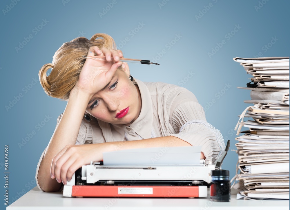 Fototapeta premium Desk. A bored office worker sitting behind a large stack of