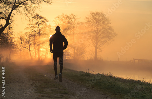 Trail runner during a foggy, spring sunrise in the countryside.