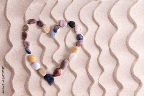 Decorative pebble heart on golden beach sand photo