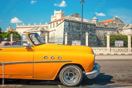 Canvas Print Vintage car parked next to an old castle in Havana