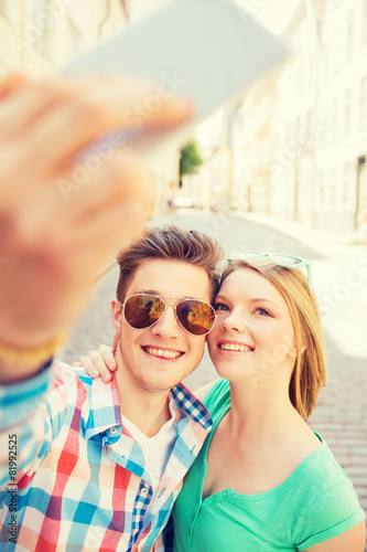 smiling couple with smartphone in city