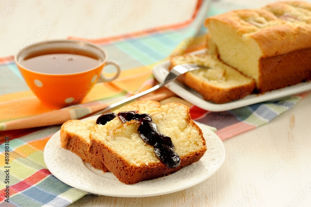 Mascarpone cake slice, cup of tea in orange teacup, blueberry ja