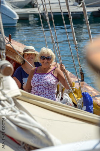 Two women among ropes of pleasure yacht in summer sunlight.