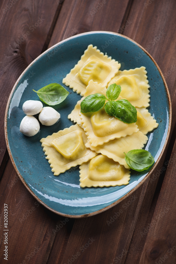 Square ravioli with mozzarella stuffing and basil, studio shot Square ravioli with mozzarella stuffing and basil, studio shot