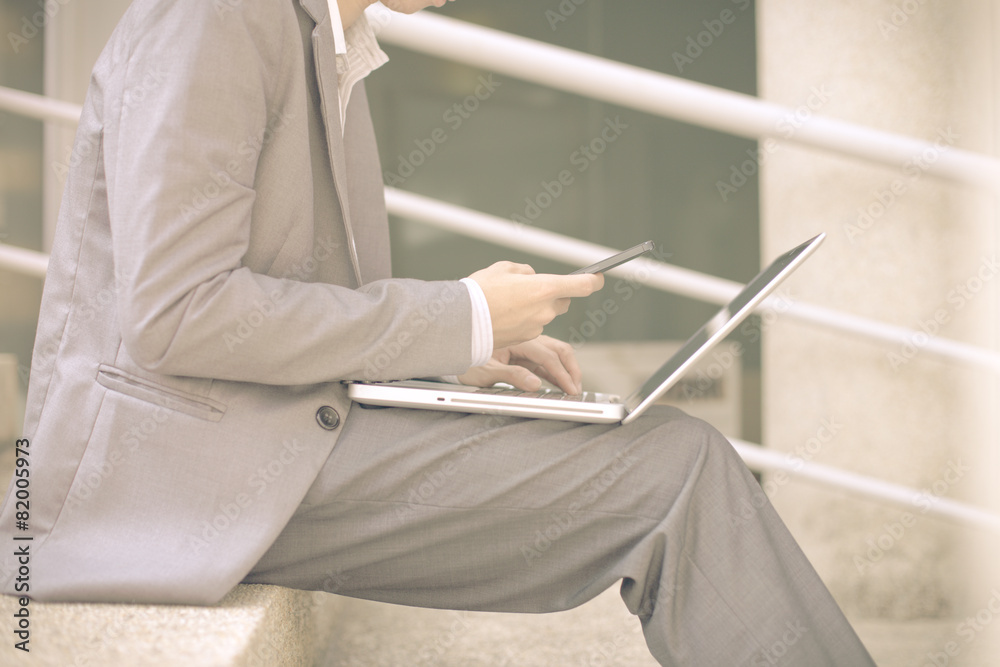 Businessman using laptop pc and mobile phone. He is sitting on a