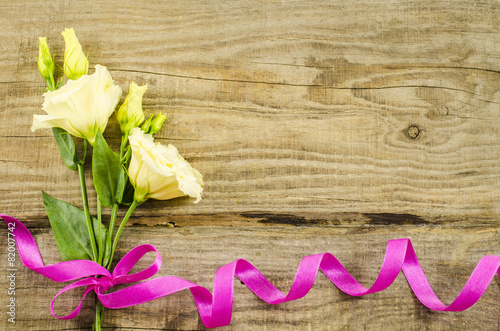 Empty wooden background with colorful flowers and pink ribbon