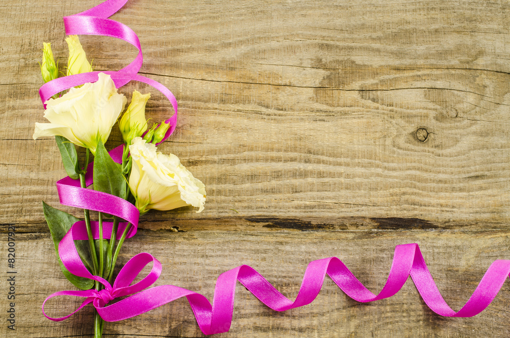 Empty wooden background with colorful flowers and pink ribbon