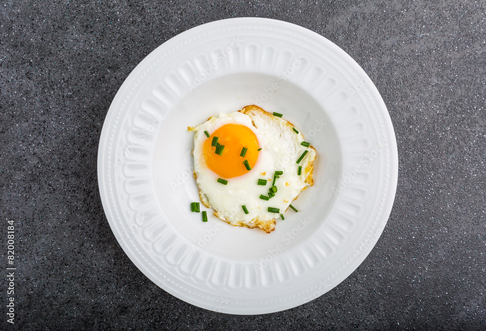 Fried egg with chives on white plate Fried egg with chives on white plate