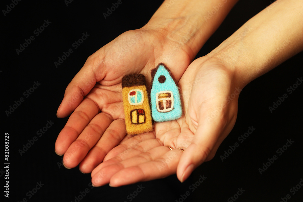 toy houses in woman hands, black background