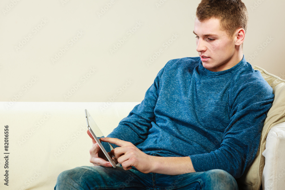 Young man with digital tablet sitting on couch Young man with digital tablet sitting on couch
