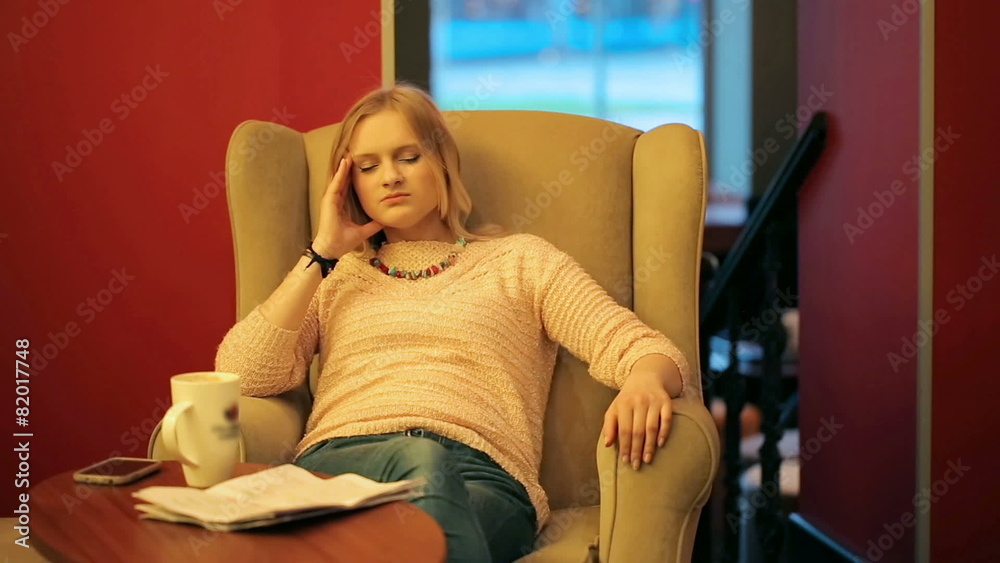 Girl sitting on the armchair in the cafe with headache
Girl sitting on the armchair in the cafe with headache
