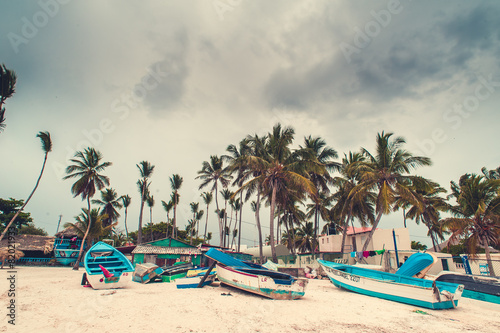 Untouched tropical beach with palms and fishing boats in
