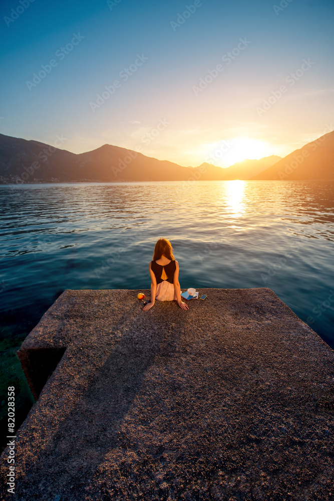 Woman sitting on the pier at sunrise