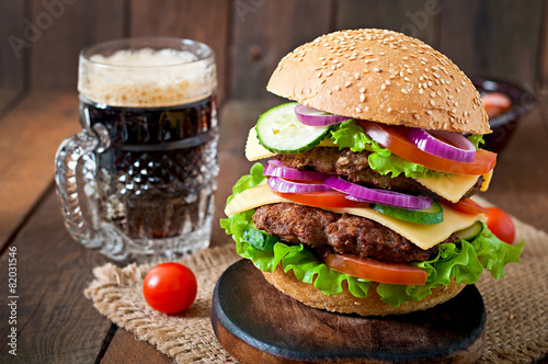 Big juicy hamburger with vegetables and beef on a wooden table