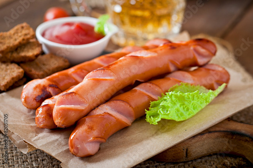 Grilled sausages, crackers and beer on a wooden background 