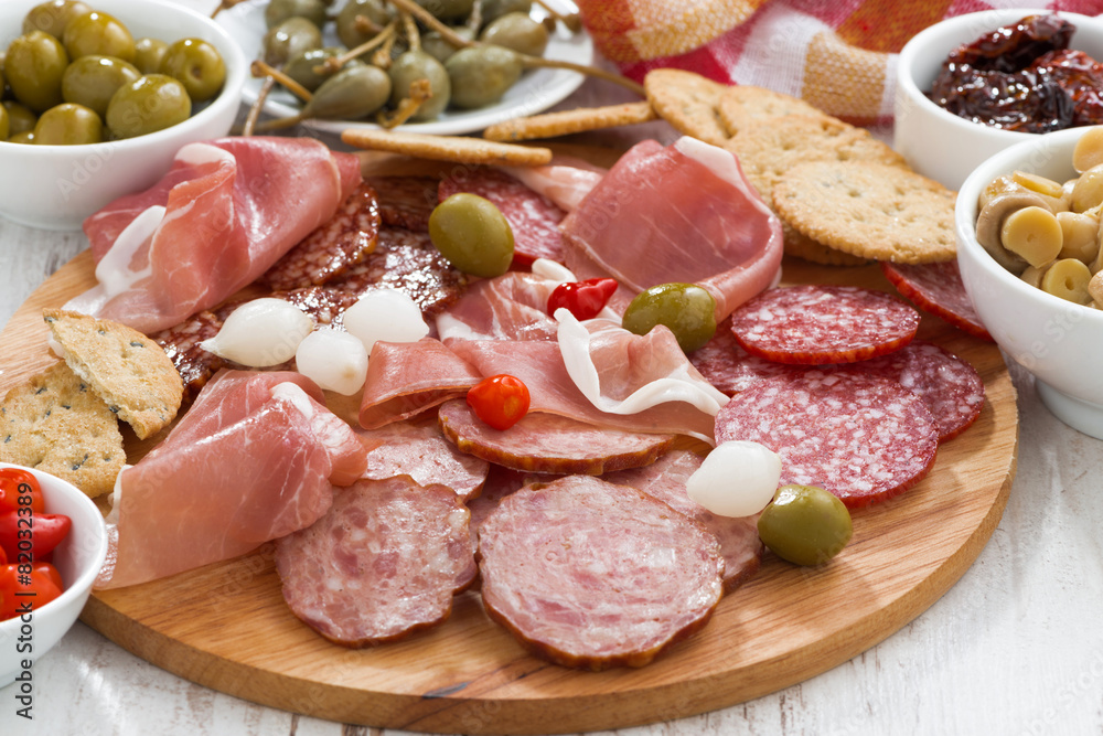 Assorted deli meat snacks, sausages and pickles on board