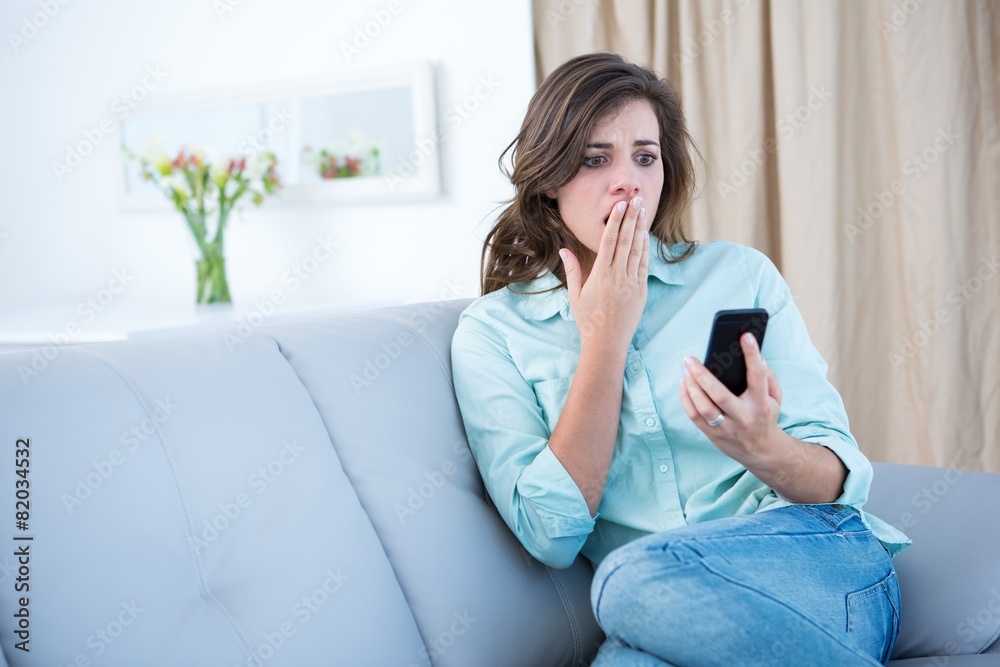 Surprised brunette looking at her smartphone Surprised brunette looking at her smartphone
