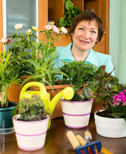 Mature housewife working with fresh flowers in pots