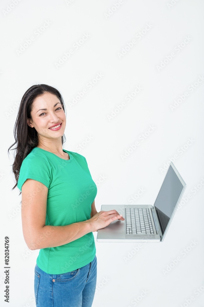 Naklejka premium Smiling brunette using laptop