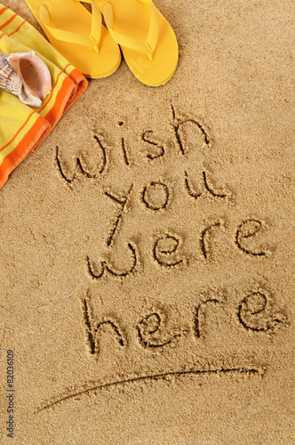 Fotografie Wish you were here classic postcard or post card message written in sand on a tr