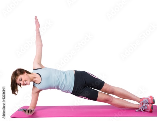 Pretty brunette doing side plank on exercise mat