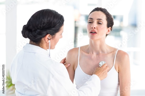 Doctor listening to patients chest with stethoscope