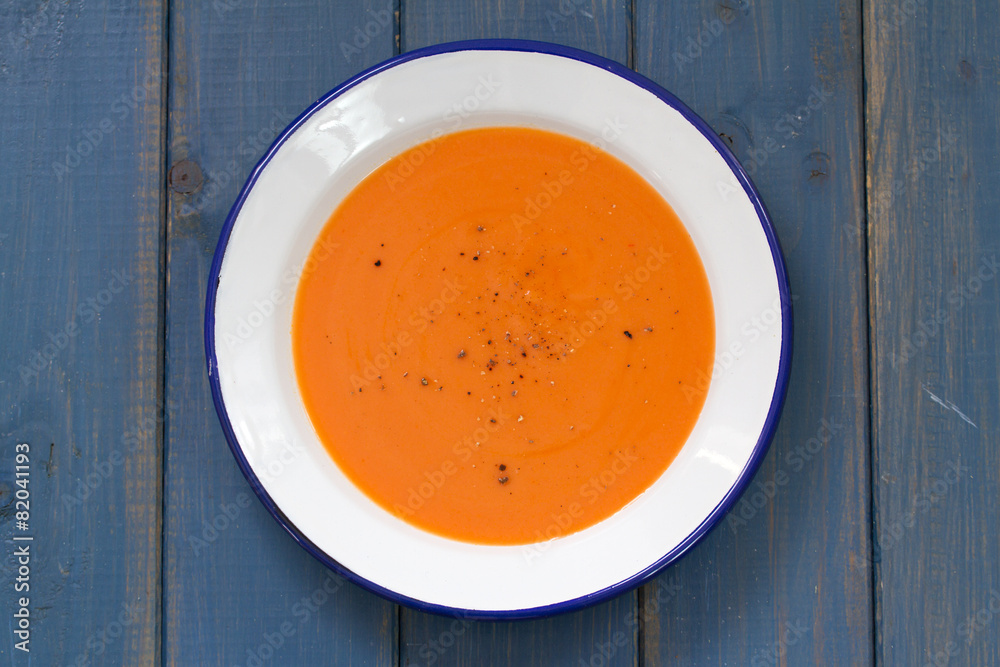 tomato soup in white plate on blue background tomato soup in white plate on blue background