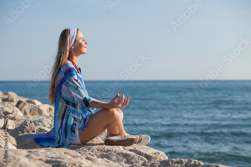 Happy young woman meditating at seacoast