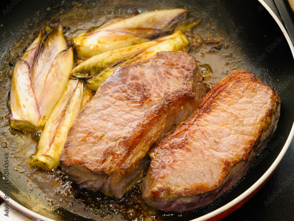 Two tasty pieces of beef tenderloin with endives cooked in a pan Two tasty pieces of beef tenderloin with endives cooked in a pan