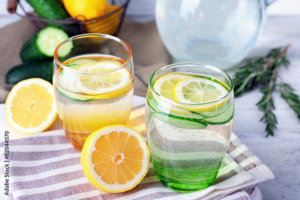Fresh water with lemon and cucumber in glassware on wooden table, closeup Fresh water with lemon and cucumber in glassware on wooden table, closeup