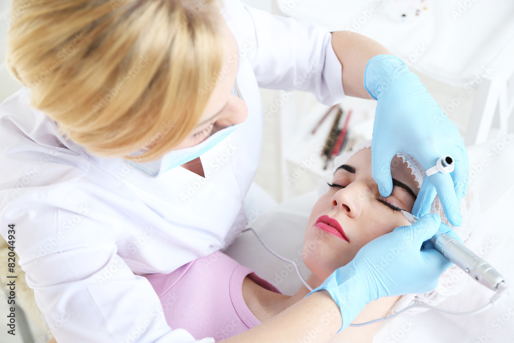 Cosmetologist applying permanent make up on eyes, close-up Cosmetologist applying permanent make up on eyes, close-up