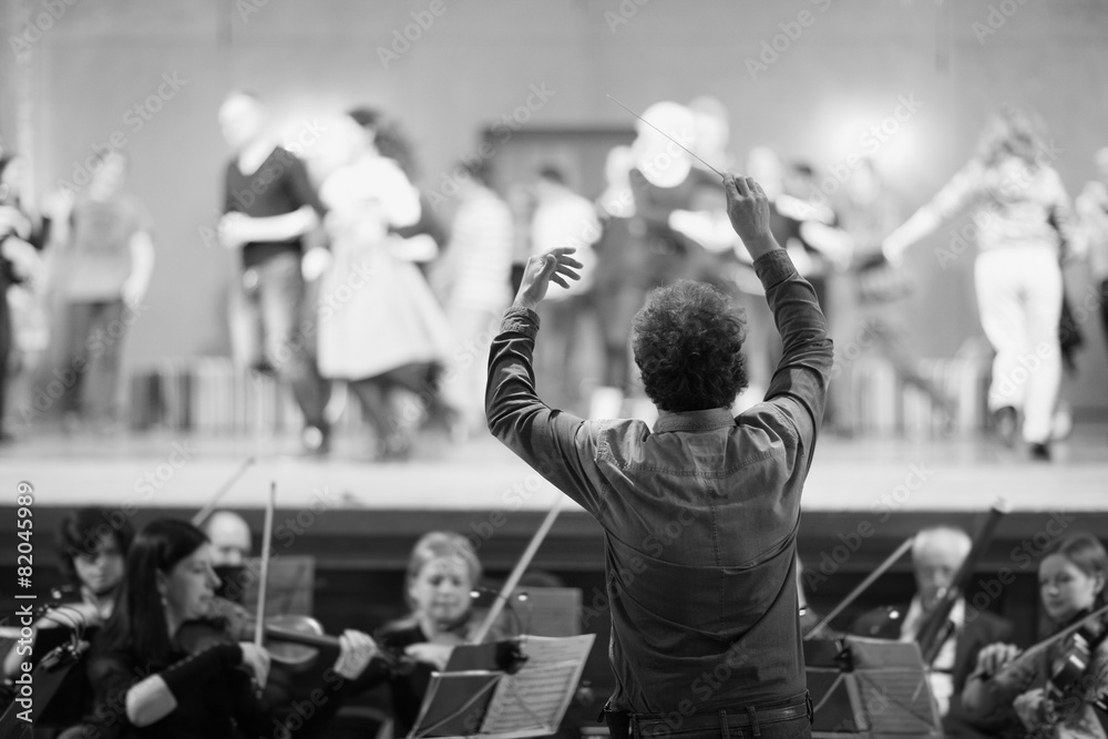 Fototapeta premium Dyrygent orkiestry prowadzący muzyków w teatrze
