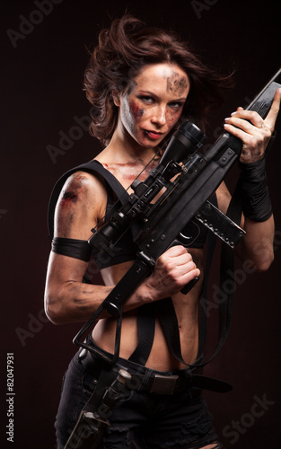 Beautiful young woman holding an automatic assault rifle. 