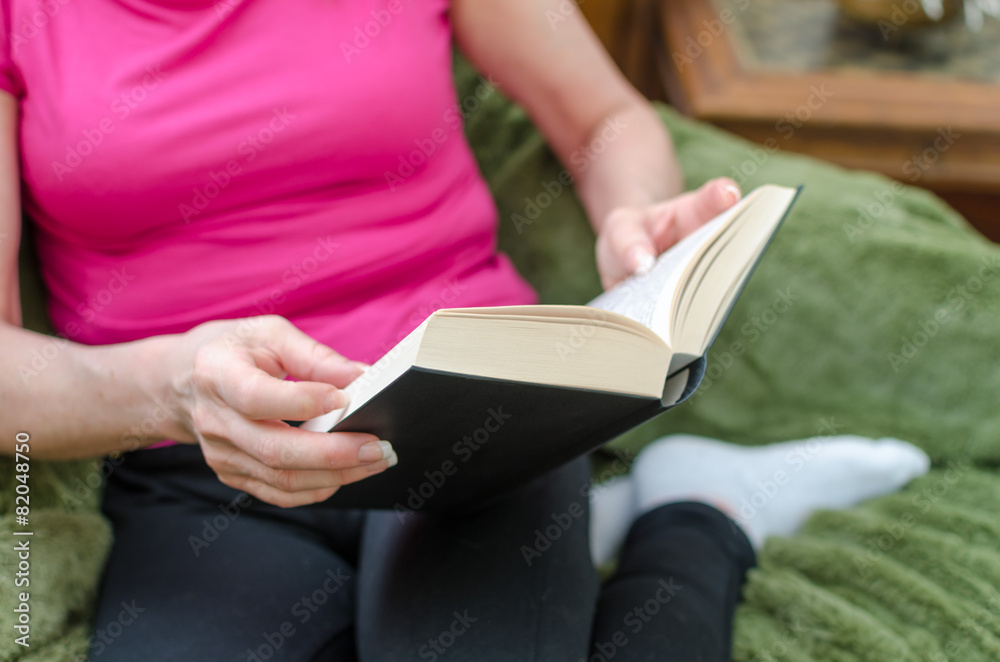 Woman reading a book on a couch Woman reading a book on a couch