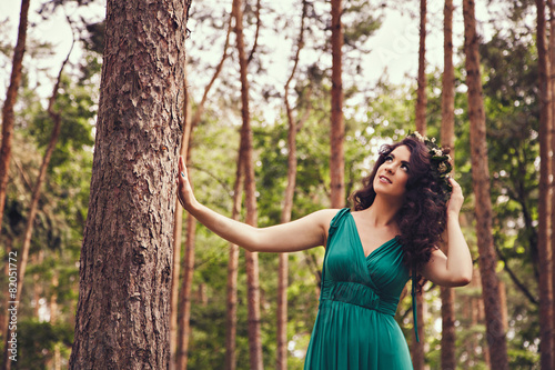 Pretty brunette with wreath in the forest looking up