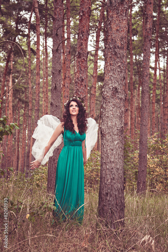 Pretty girl with angel wings among trees