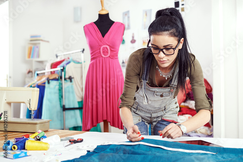 Young female designer measuring textile material