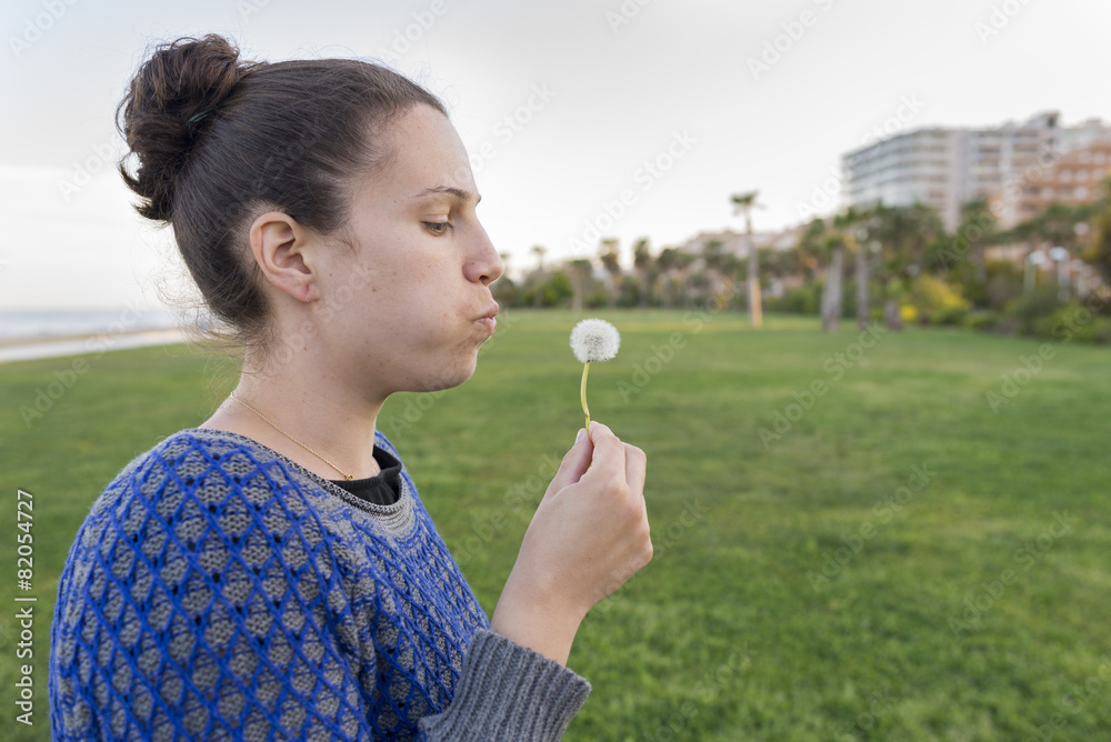 Chica soplando un diente de león. Chica soplando un diente de león.