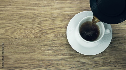 Pouring freshly brewed coffee to a classic cup, top view